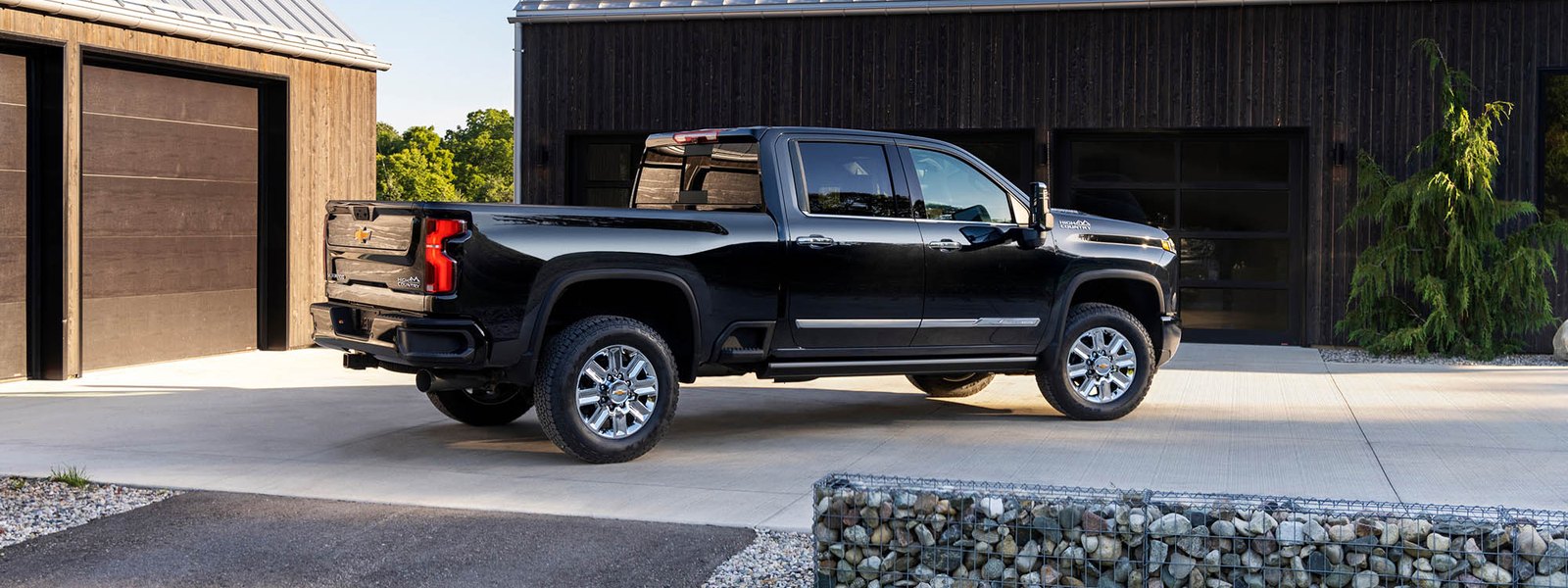Chevrolet Silverado 3500HD crew cab with single rear wheels, parked on a driveway beside a timber outbuilding
