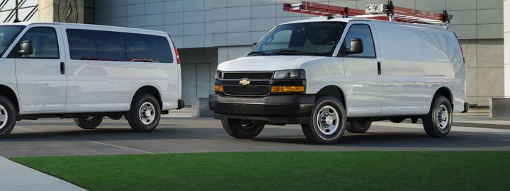 Chevrolet Express Cargo Van with a roof ladder rack, parked at a commercial building